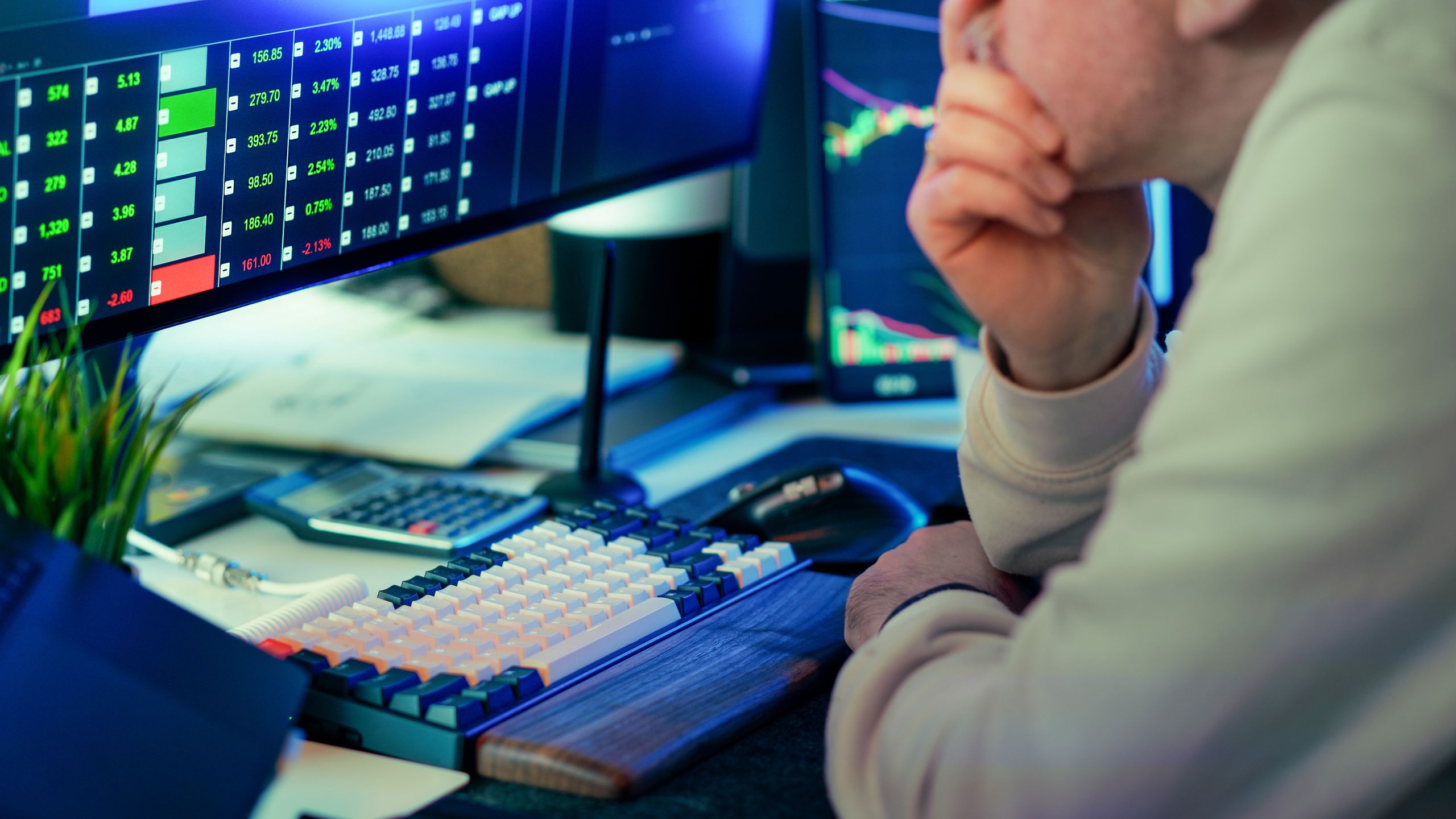 Professional reviewing financial market data on multiple screens