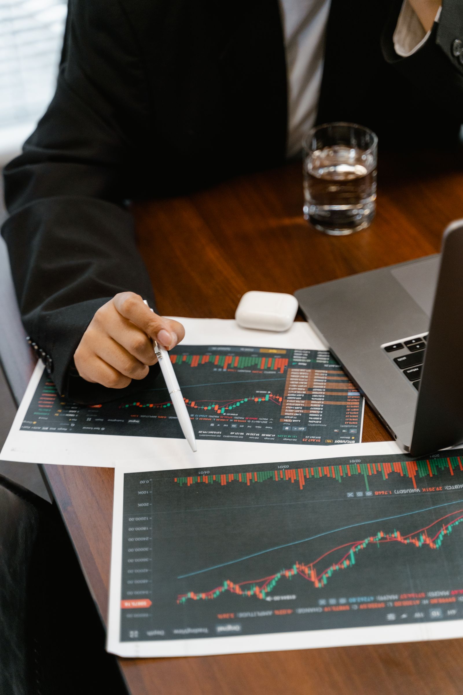 Investment professional screening market data and printed charts at a desk