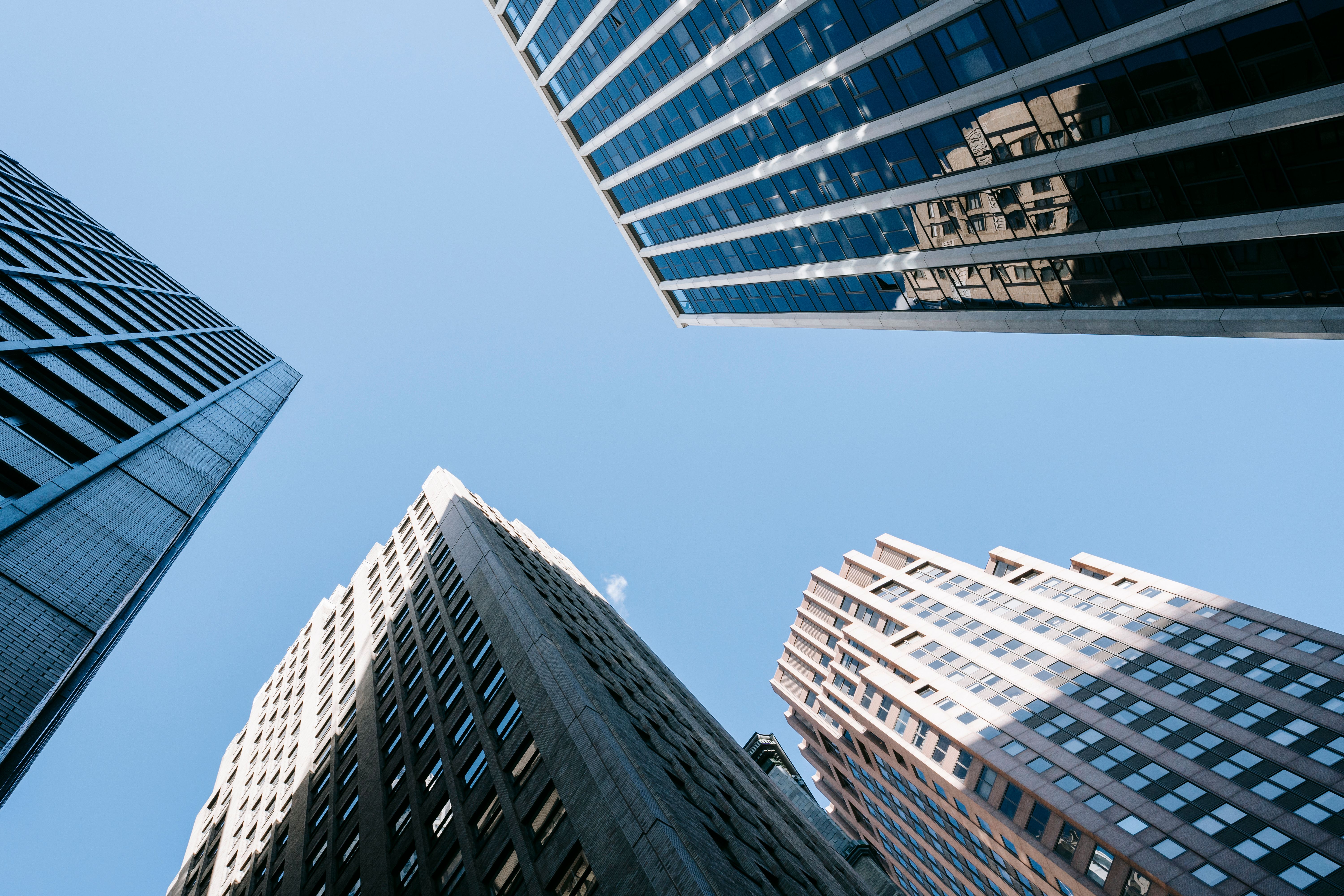 Looking up at modern office buildings against a clear blue sky